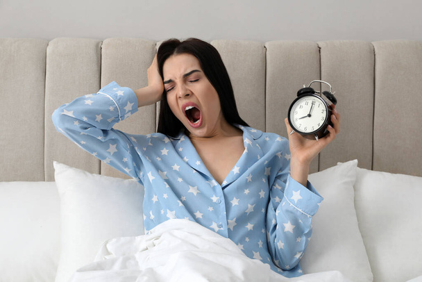 Overslept woman with alarm clock in bed. Being late concept - Foto, Bild