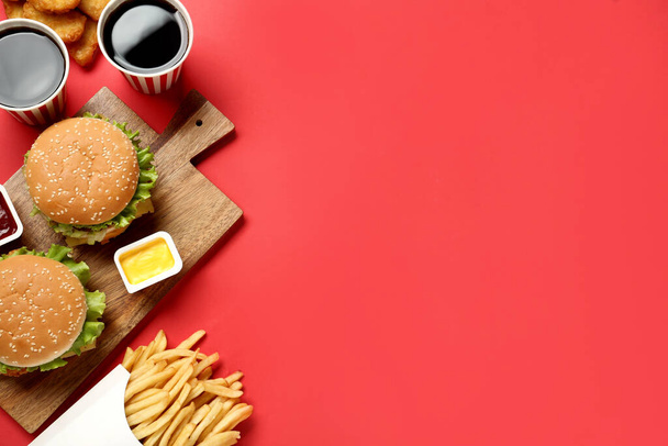 Flat lay composition with delicious fast food menu on red background. Space for text - 写真・画像