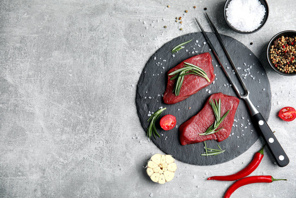Fresh raw meat steaks and spices on light grey table, flat lay. Space for text - 写真・画像