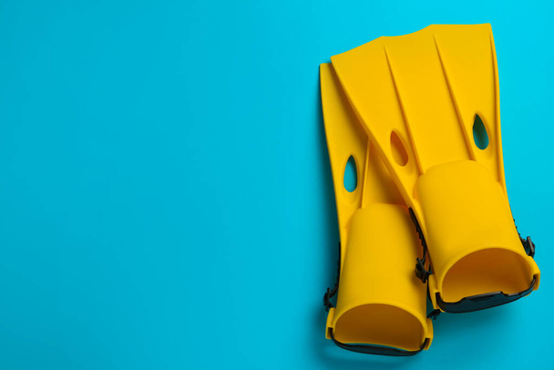 Pair of yellow flippers on light blue background, flat lay. Space for text - Photo, image