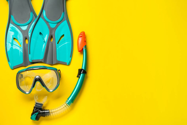 Pair of turquoise flippers and mask on yellow background, flat lay. Space for text - Fotó, kép