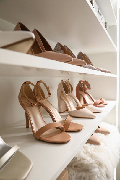Different stylish women's shoes on shelving unit - Fotó, kép