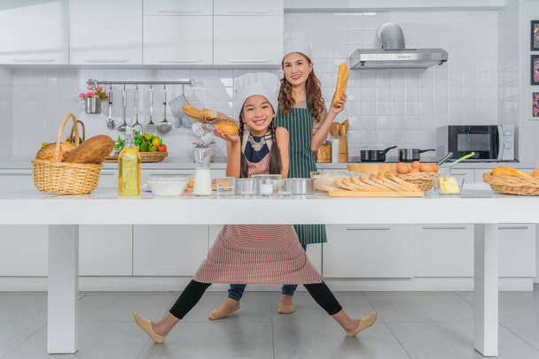 asian mother and little daughter having fun baking bakery together in kitchen at home - Zdjęcie, obraz