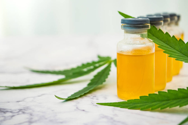 Aceite de cannabis en los viales con hojas verdes sobre la mesa de mármol. Concepto de medicina alternativa. - Foto, Imagen