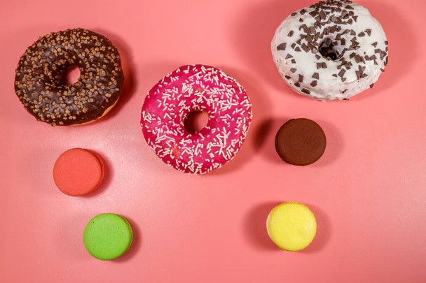Tasty donuts and macaroons on pink background. Top view - Photo, Image