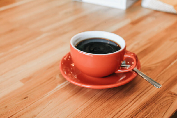 Hand hält eine heiße Tasse Kaffee auf einem Holztisch. Morgens Tasse Kaffee. Hipster-Ton. Selektiver Fokus, verschwommener Hintergrund. - Foto, Bild