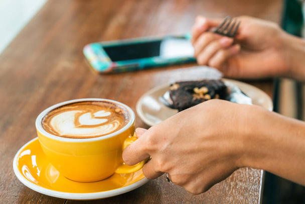 detail muže držícího šálek kávy a smartphone s rozmazaným pozadím - Fotografie, Obrázek
