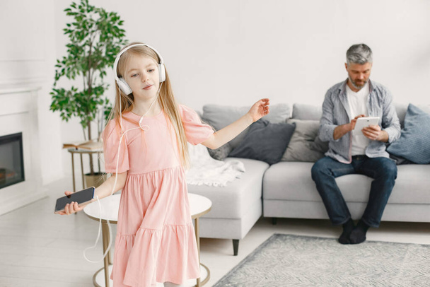 Little girl listening music in headphones with grandfather - Photo, image