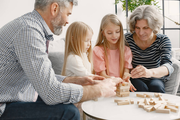 Grandparents play tower game with two girls - Foto, afbeelding