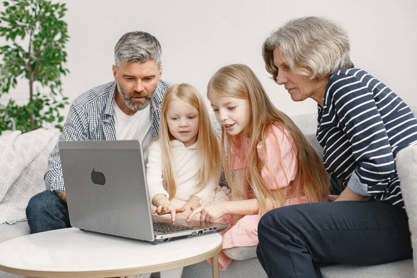 Grandarents with granddaughters using laptop in the living room - Fotó, kép