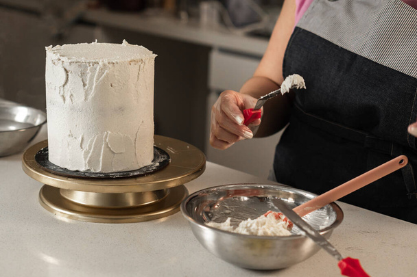 Молодая женщина украшает торт смесью сливочного крема - Фото, изображение