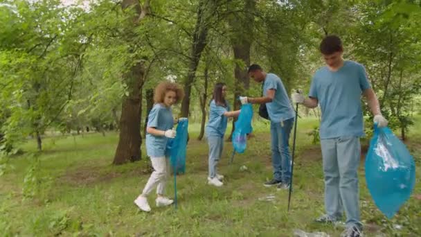 Charmantes Mädchen hilft hübschem jungen Mann, Müllsack im Freien zu öffnen - Filmmaterial, Video