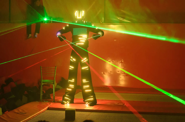 Un danseur en costume LED de couleur danse avec un laser dans les mains - Photo, image