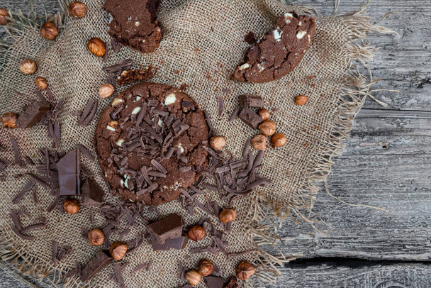 Chocolate cookies, hazelnuts and pieces of dark chocolate on the rustic kitchen table. Top view - Foto, afbeelding