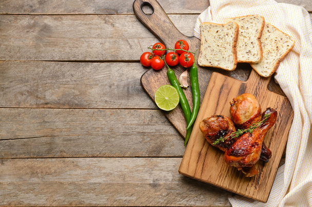 Board with roasted chicken legs on wooden background - Photo, Image