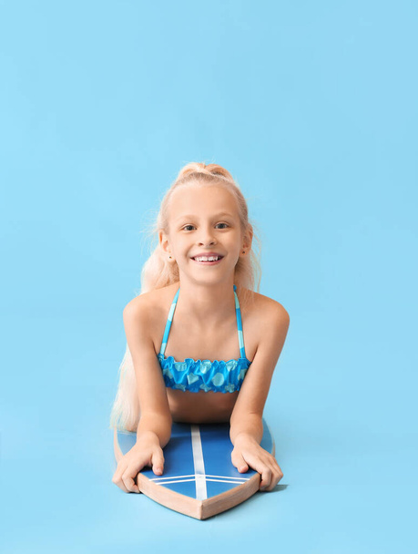 Cute little girl with surfboard on color background - Foto, immagini
