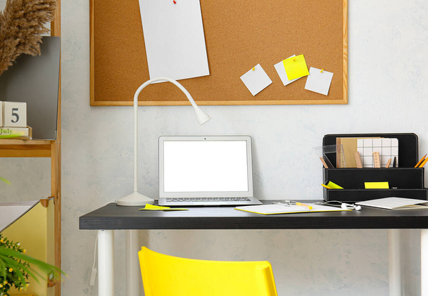 Σύγχρονη χώρο εργασίας με φορητό υπολογιστή κοντά στο φως τοίχο - Φωτογραφία, εικόνα