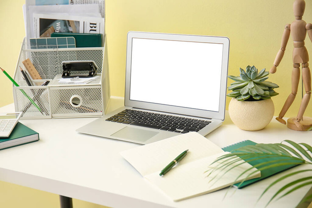 Moderne werkplek met laptop in de buurt van kleur muur - Foto, afbeelding