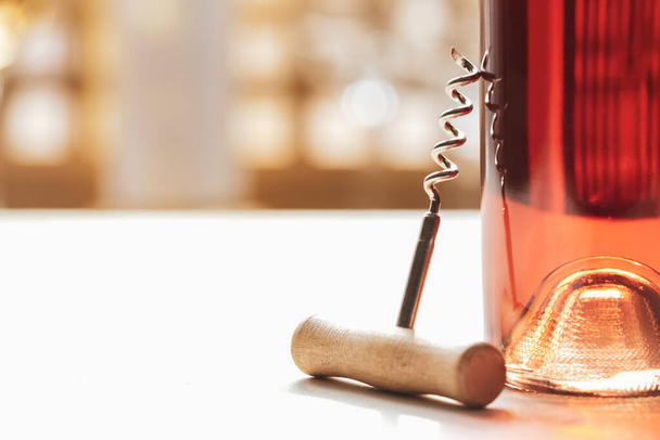 Bottle of exquisite wine and corkscrew on table, closeup - Fotó, kép