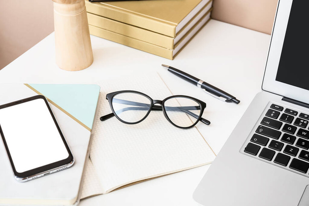 Stylish eyeglasses with notebook and mobile phone on table - Zdjęcie, obraz