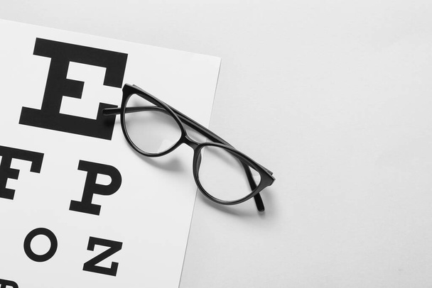 Κομψά γυαλιά με οφθαλμολογικό διάγραμμα σε ανοιχτό φόντο, κοντινό πλάνο - Φωτογραφία, εικόνα