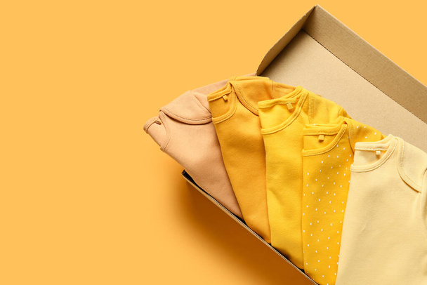 Box with baby clothes on color background - Fotografie, Obrázek