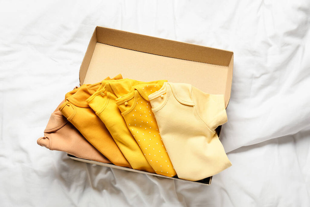 Κουτί με μωρουδιακά ρούχα στο κρεβάτι - Φωτογραφία, εικόνα