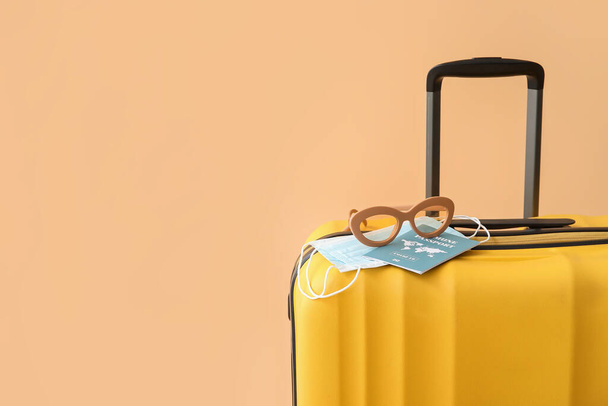 Gepackter Koffer mit Immun-Pass, medizinischen Masken und Sonnenbrille auf farbigem Hintergrund - Foto, Bild
