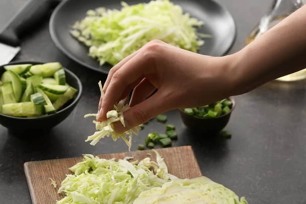 Female chef cooking tasty cabbage salad on table in kitchen, closeup - Фото, зображення