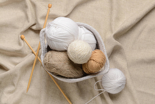 Basket with knitting yarn and needles on fabric background - Фото, зображення