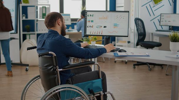 Парализованный менеджер, работающий в стартапе, сидит в инвалидном кресле - Фото, изображение