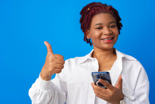 African american woman using smartphone against blue background - Фото, изображение