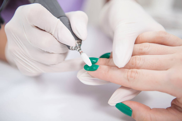 Woman having green nail gel removed by professional manicurist using nail drill - Foto, afbeelding