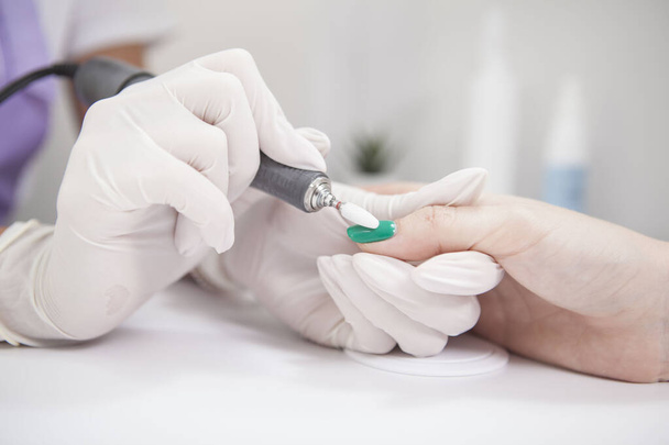 Close up of manicurist removing nail gel with nail file drill - Photo, image