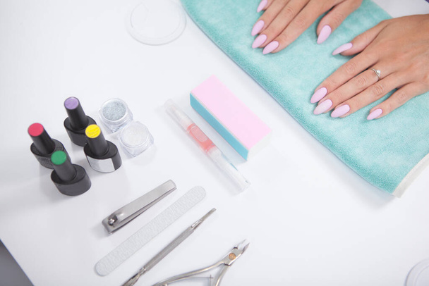 Cropped shot of manicure equipment and female hands on white table at nail salin - 写真・画像