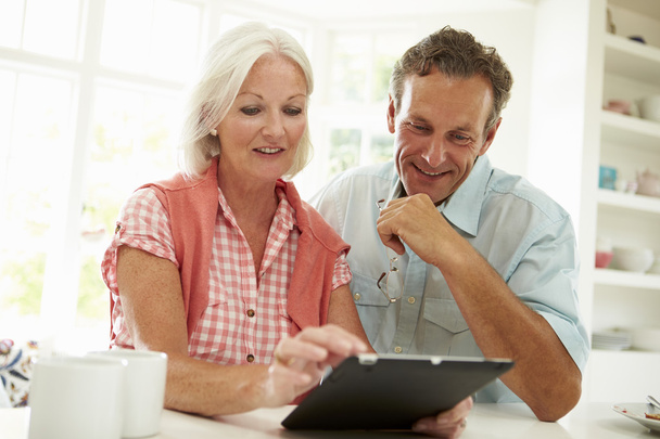 Middle Aged Couple Looking At Digital Tablet - Fotó, kép