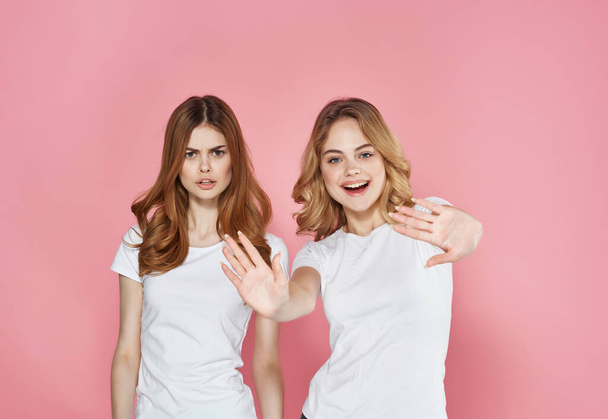 two sisters white t-shirts hug friendship emotions pink background - Photo, Image