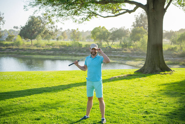 Male golf player on professional golf course. Golfer man with golf club taking a shot. - Fotó, kép