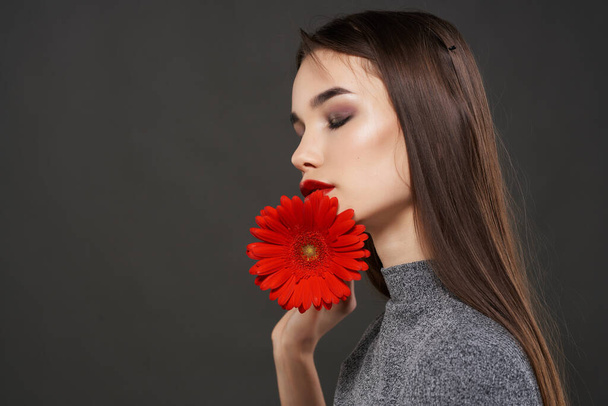 брюнетка з червоною квіткою біля обличчя розкішна косметична романтика
 - Фото, зображення