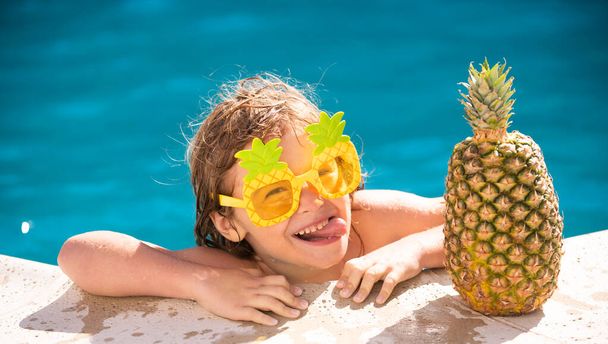 Summer vacation, funny kid having fun in pool. Cute kid in swimming pool. Summer pineapple fruit. Funny face. - Fotó, kép