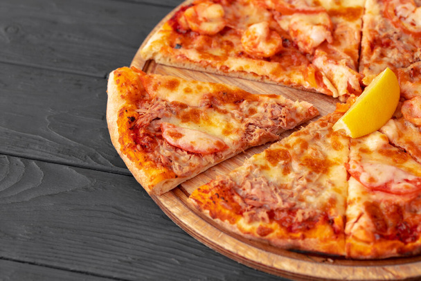 Close up of freshly baked pizza on black wooden table - Foto, Imagen