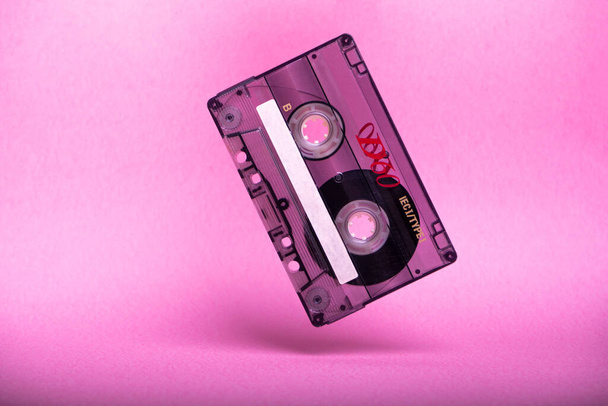 spadające vintage kasety audio na różowym tle. - Zdjęcie, obraz