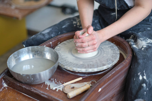 Закройте женские руки, сделайте посуду из глины. женские руки, работающие на гончарных колесах. Мастер-гончар работает в мастерской - Фото, изображение