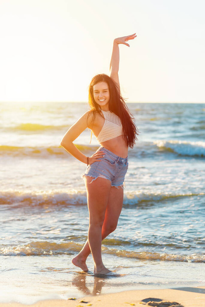 Красива сексуальна дівчина на морському пляжі в повсякденному одязі дивиться на камеру на заході сонця. Крупним планом модна дівчина. Красивий портрет моделі зовні
. - Фото, зображення
