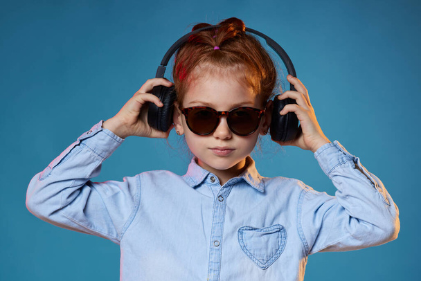 redhead child girl in sunglasses and wireless headphones - Foto, afbeelding