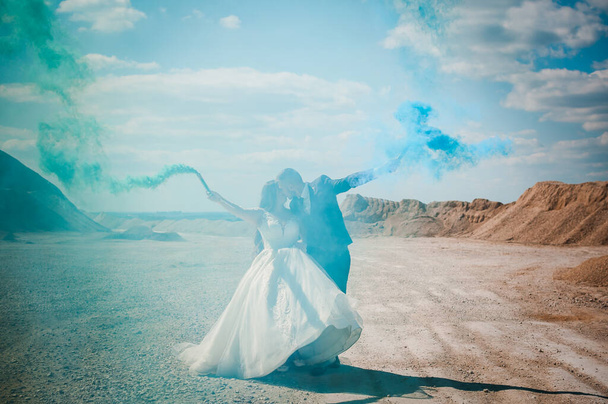 Хлопець і дівчина обіймаються і тримають кольоровий дим в руках
 - Фото, зображення