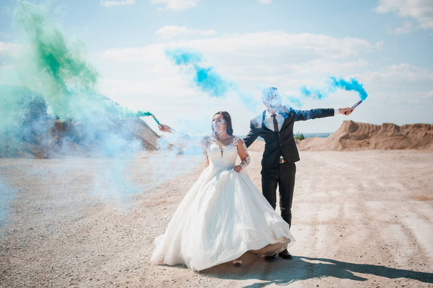 Парень и девушка обнимаются и держат в руках цветной дым. - Фото, изображение