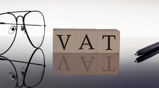 Primer plano de los bloques de madera IVA sobre fondo negro con gafas y bolígrafo - Foto, imagen