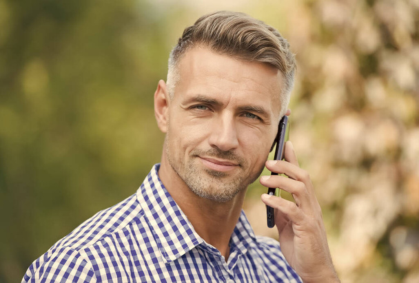 assistance by phone. communication with modern devices. cheerful man speak on mobile phone. handsome businessman has groomed graying hair. mature guy is always online. agile business concept - Photo, Image