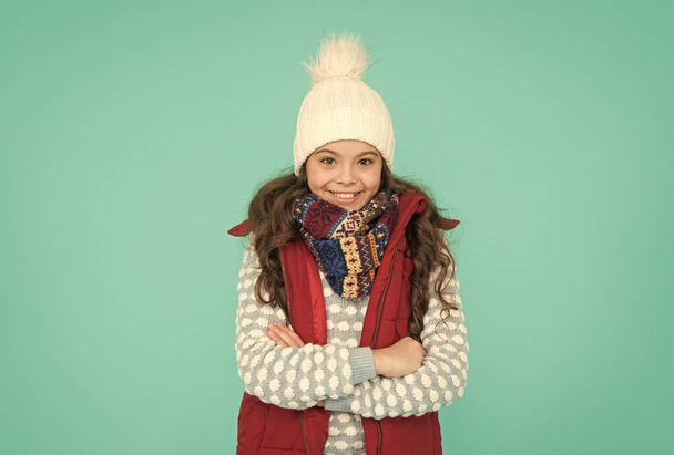 child with long curly hair in knitted hat. cold season style christmas activity. childhood happiness. thermal clothing. happy teen girl wear warm clothes. winter kid fashion. Trendy and stylish - Foto, imagen